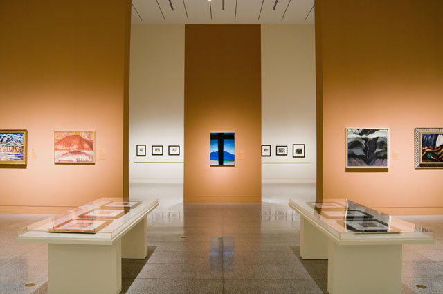 ©Museum of Fine Arts, Houston . Installation photo by Thomas DuBrock. View of MFAH installation showing the “Southwest” gallery and looking towards the “Dustbowl” gallery. Georgia O'Keeffe's Black Cross with Stars and Blues (1929; Mr. and Mrs. Peter Coneway) commands the center of the gallery. This installation shot demonstrates the dominant style for the layout of the exhibition, where important objects were given pride of place, as they were in LACMA's installation (see Fig. 10).