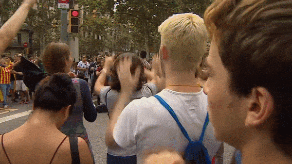 Gif of a crowd of Catalonian independence protesters clapping rhythmically with flags tied around their backs